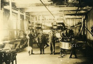 3 men in a filing room surrounded by machinery