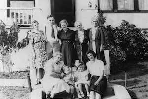 Multiple family generations standing and sitting in front of a house