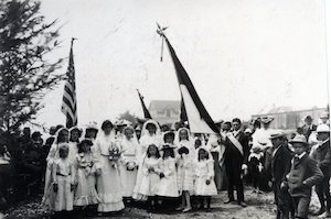 Young woman holding a bouquet surrounded by girls with men standing to the side.