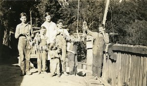 Seven children holding up small strings of fish