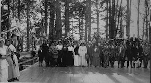 Crowd of people facing the camera standing on wooden platform outdoors