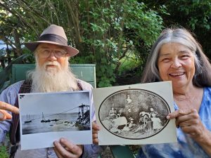 Older man and woman holding up black and white photographs