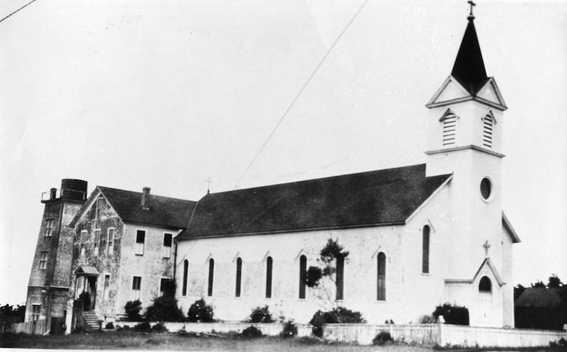Church with steeple. Two-story dormitory behind church.